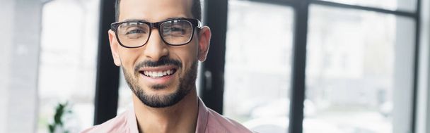 Χαρούμενος μουσουλμάνος επιχειρηματίας με γυαλιά ηλίου κοιτάζοντας κάμερα στο γραφείο, πανό  - Φωτογραφία, εικόνα