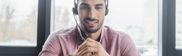 Smiling muslim businessman in headset in office, banner  - Fotó, kép