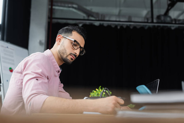 Muszlim üzletember szemüvegben dolgozik a laptop közelében az irodában  - Fotó, kép