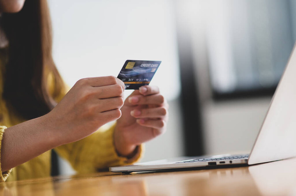 Young woman holding credit card in hand and laptop on the table, Online shopping, Credit card payment,Close up shot. - Foto, Bild
