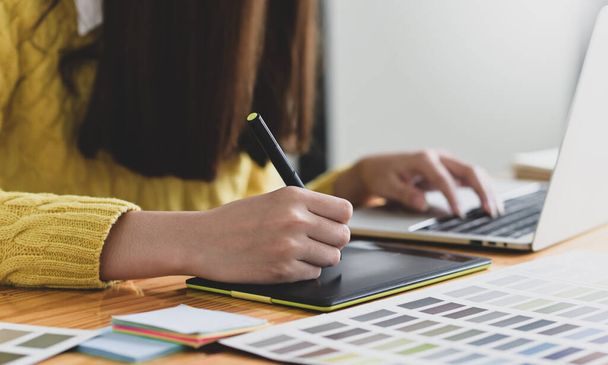 female designer sketching on a digital graphic tablet, A woman writing on digital board with pen and working on laptop, Designer's desk. - Foto, Imagem