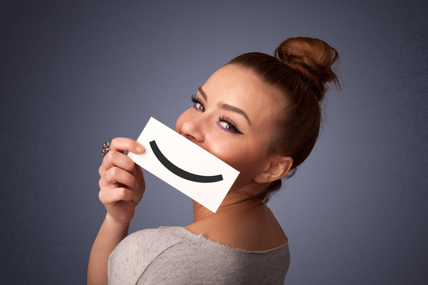 Feliz bonita mujer sosteniendo tarjeta con divertido smiley
 - Foto, Imagen