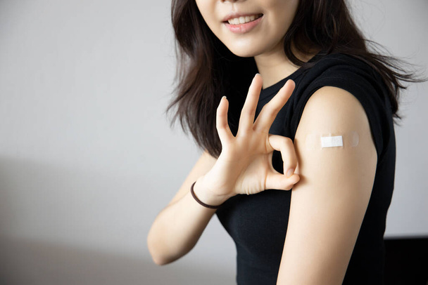 Egészséges ázsiai nő kap oltott immunitás, amely rendben kézjel, hogy terjessze ki a vakcina, koncepció az ajánlott oltás, oltás, oltott beteg, vakcina roll-out program - Fotó, kép