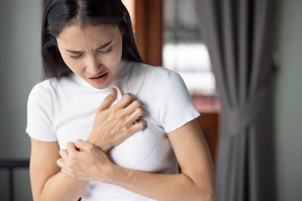 Frau mit plötzlichem Herzinfarkt, kranke Frau mit akutem Herzinfarkt, Konzept der Notfallversorgung, asiatisches Modell für junge erwachsene Frau - Foto, Bild