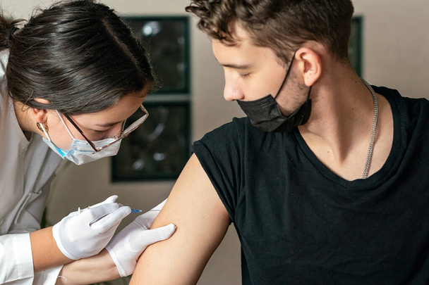 Genç adam omzuna iğne yaptı. Koronavirüs aşısı. Koronavirüse karşı aşı.  - Fotoğraf, Görsel