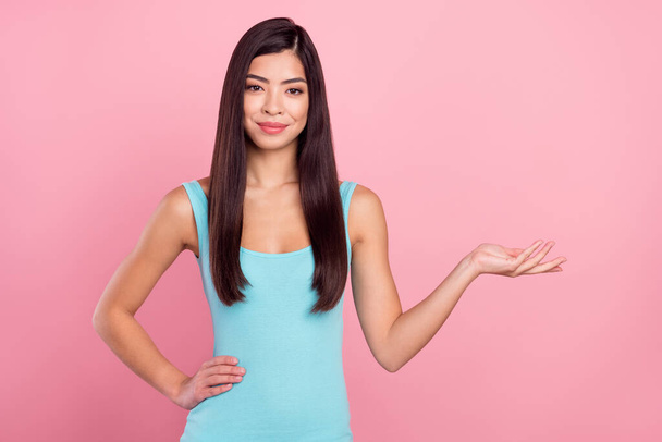 Photo portrait woman wearing blue dress smiling showing blank space with hand isolated pastel pink color background - Φωτογραφία, εικόνα