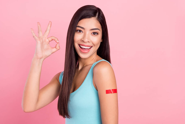 Photo of impressed millennial lady show okey sign with red plaster wear blue top isolated on pink color background - Photo, Image