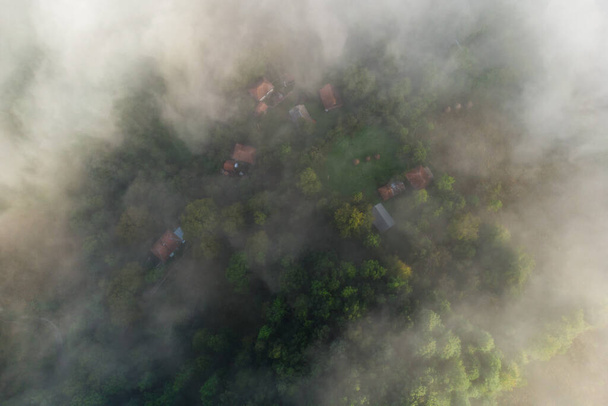 Veduta aerea del paesaggio montano con nebbia mattutina, ai margini della foresta, in Romania - Foto, immagini