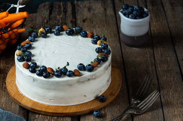 κέικ καρότου με καρύδια και blueberryand σε σκούρο φόντο ξύλο. Τοπικό φαγητό. Παραδοσιακή αμερικάνικη τούρτα. Τούρτα για την ημέρα των Ευχαριστιών. Φθινοπωρινή τούρτα - Φωτογραφία, εικόνα