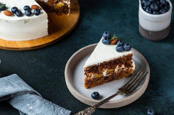 piece of carrot cake with walnuts and blueberry on dark wood background. Local food. Traditional american cake. Cake for thanksgiving day. Autumn cake - 写真・画像