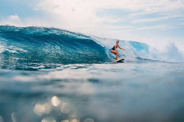 Surfer girl at surfboard on blue wave in tropical ocean. Sporty woman during surfing. - Photo, Image