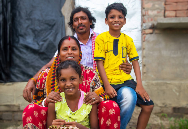 I genitori rurali indiani e i loro due figli seduti di fronte alla casa di famiglia nel villaggio - Foto, immagini