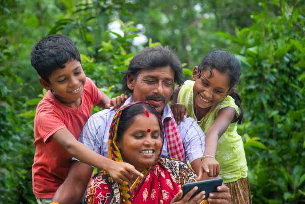 Padres rurales indios y sus dos hijos viendo películas en el campo agrícola - Foto, Imagen
