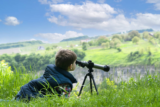 Petit garçon regardant dans le verre espion sur la campagne ensoleillée champ - Photo, image