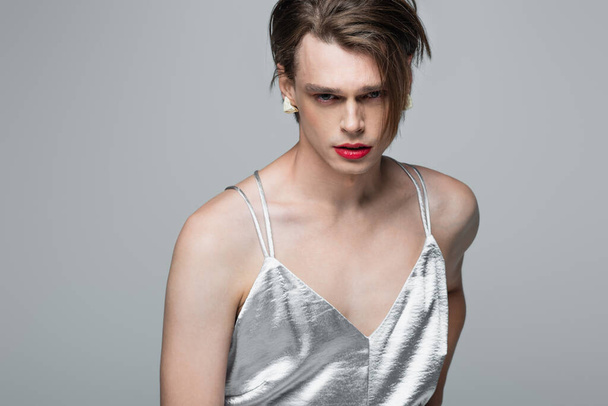 young transgender man with makeup posing in slip dress isolated on grey - Foto, afbeelding