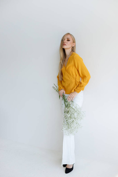 blogger ve stylovém oblečení s bílými květy na šedém pozadí - Fotografie, Obrázek