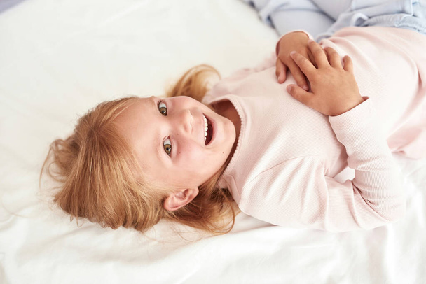 Smiling little girl child relax on cozy bed at home - Фото, зображення