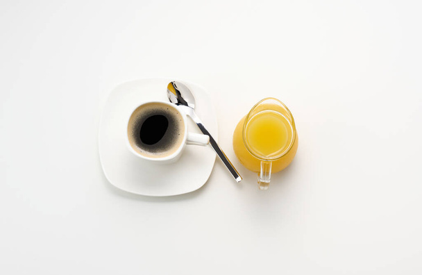 freshly squeezed juice in a glass transparent decanter, a cup of coffee, honey and oatmeal on a white table. Morning breakfast, top view - Photo, Image