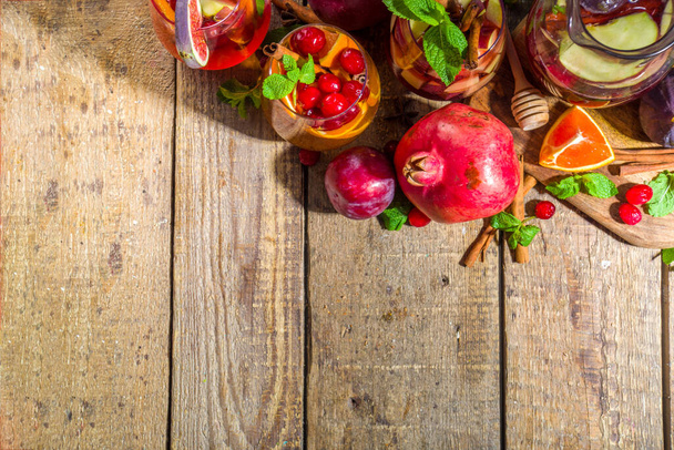 Traditionele herfst winter drinken hete kruidige sangria - rood, roze, wit. Met cider, roze rode wijn, appels, sinaasappels, granaatappel, cranberry, pruim, vijgen, kaneelstokjes. Houten rustieke tafel kopieerruimte - Foto, afbeelding