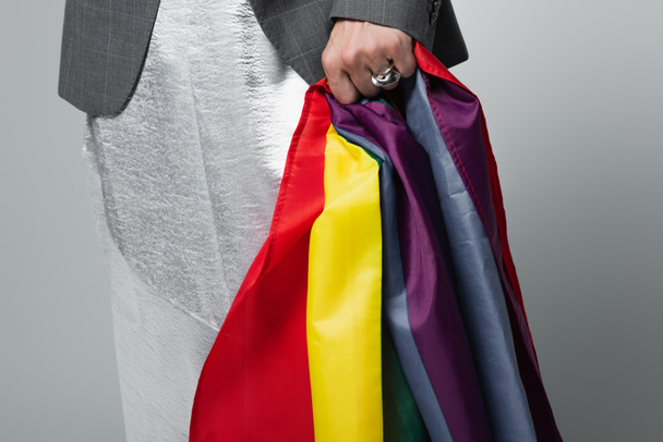 καλλιεργημένη άποψη του τρανσέξουαλ άνδρα με ολίσθηση φόρεμα εκμετάλλευση σημαία Igbt απομονώνονται σε γκρι - Φωτογραφία, εικόνα