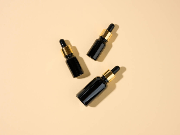 glass cosmetic brown bottles with a pipette on a beige background. Cosmetics SPA branding mockup, top view - Foto, Bild