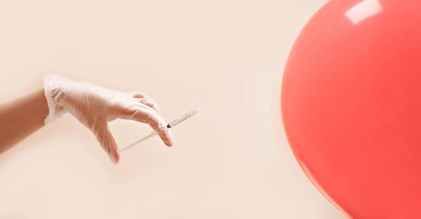 Concept with syringe and hand in gloves injecting a balloon. Spa, medicine, healthcare, treatment, beauty concept - Photo, image