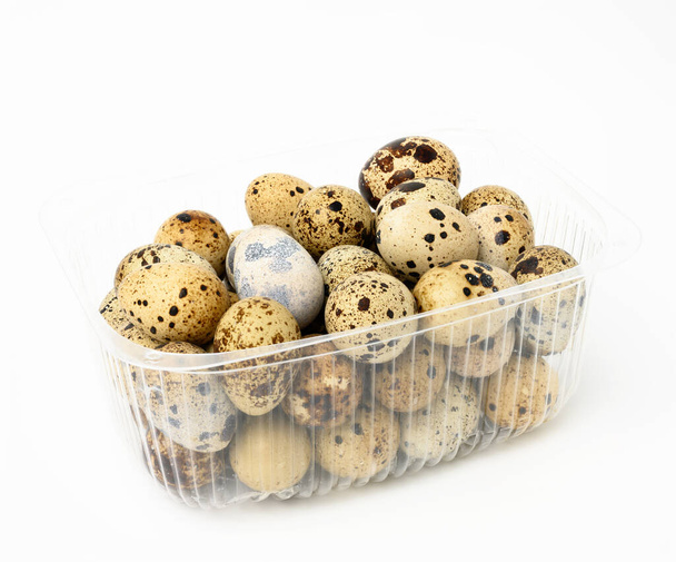 svazek syrových křepelčích vajec v plastové průhledné nádobě na bílém pozadí, dietní potraviny - Fotografie, Obrázek