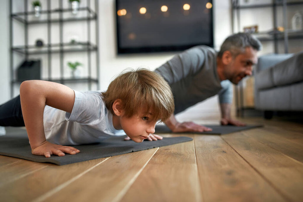 Sporty toned father and son do sport pushups - 写真・画像