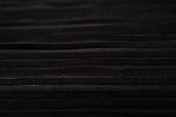 黒の布のテクスチャの背景を閉じます。デザインにはプリーツブラックのスカートを使用。柔らかいサテンの質感。水平線 - 写真・画像