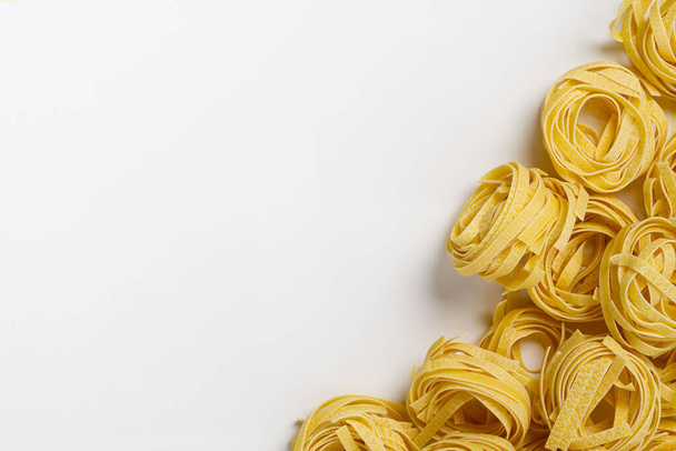 Fettuccine di pasta italiana isolate su fondo bianco. Tagliatelle crude nidi isolati su fondo bianco. Pasta tradizionale italiana - Foto, immagini