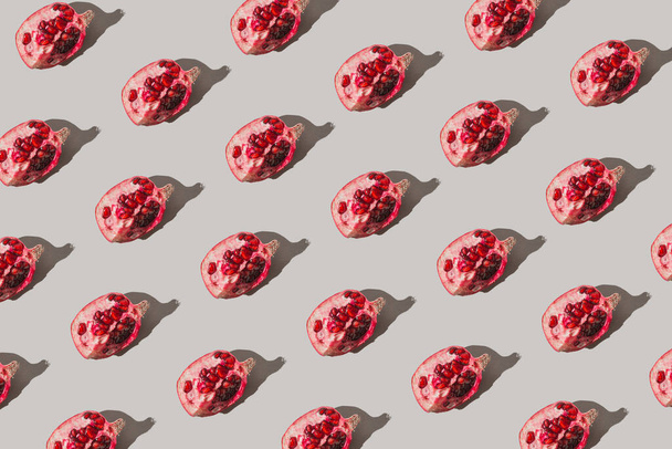 Creative pattern made of fresh slices of pomegranate on pastel grey background with sunlit. Minimal style. Top view. Flat lay . - Foto, Bild