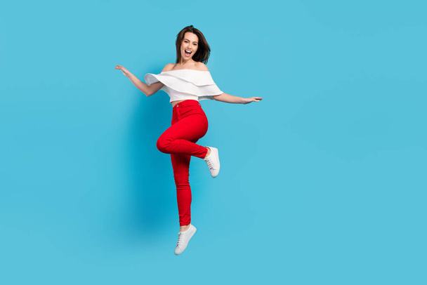 Full size photo of sweet brunette young lady jump wear blouse jeans isolated on blue color background - Zdjęcie, obraz