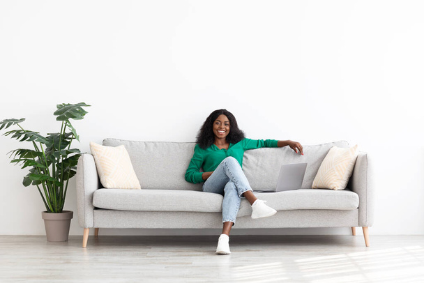 Joyful african american woman relaxing on couch at home - 写真・画像