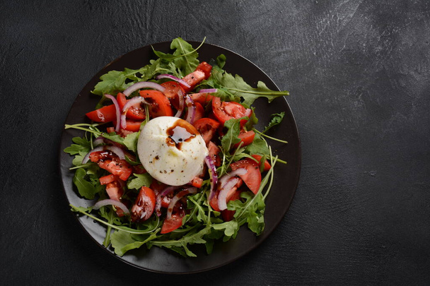 Salad with Tomatoes and Burrata cheese with basil and olive oil on dark background. Traditional Italian dish burrata cheese. Burrata served with tomatoes and arugula - Photo, Image