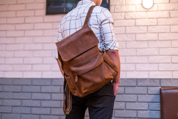 Back of man with brown leather backpack. Unisex bag for sale. Unbranded backpack. - Fotografie, Obrázek