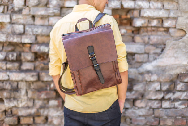 Back of man with brown leather backpack. Unisex bag for sale. Unbranded backpack. - 写真・画像