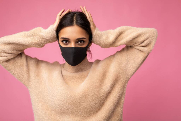 Young woman wearing an anti virus protection mask to prevent others from corona COVID-19 and SARS cov 2 infection isolated over pink background - Foto, Imagem