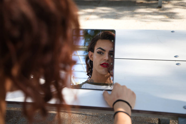 jeune femme transsexuelle latina est dans un parc où elle va commencer à faire son maquillage pour son grand changement de garçon à fille. Concept de diversité, de transgenre et de liberté d'expression homosexuelle. - Photo, image