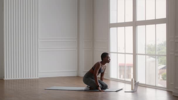 Yoga en línea. Deportiva mujer negra encendiendo la lección de video en el ordenador portátil y comenzar la práctica de meditación - Imágenes, Vídeo