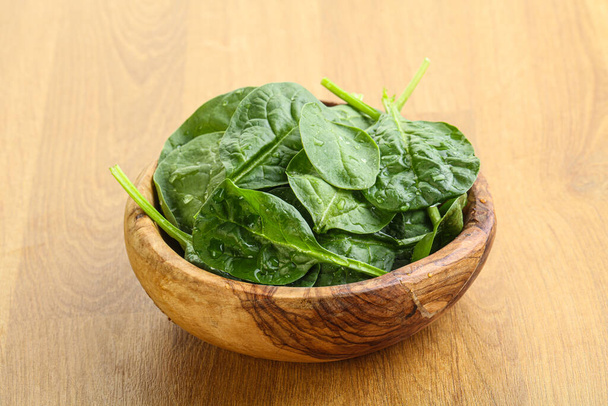 Fresh green spinach leaves in the bowl over wooden background - Photo, image