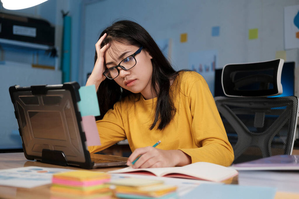 Stres wyczerpany kobieta siedzi w biurze i pracuje w godzinach nadliczbowych, jest przeciążona pracą. - Zdjęcie, obraz