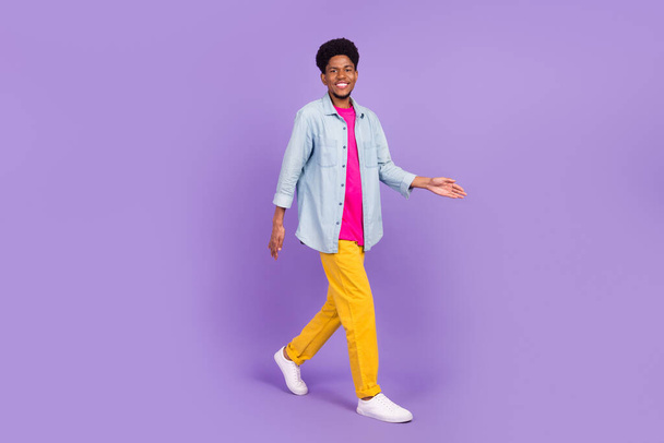 Photo of charming sweet dark skin man wear denim shirt smiling walking isolated purple color background - Фото, зображення