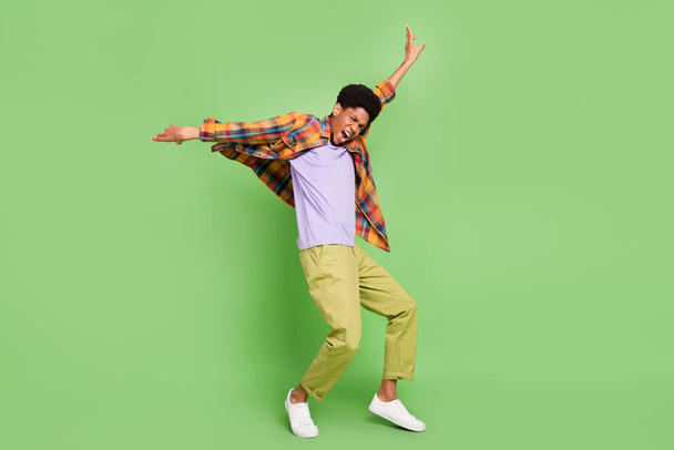 Photo of funny pretty dark skin guy dressed checkered shirt dancing arms sides smiling isolated green color background - Fotoğraf, Görsel