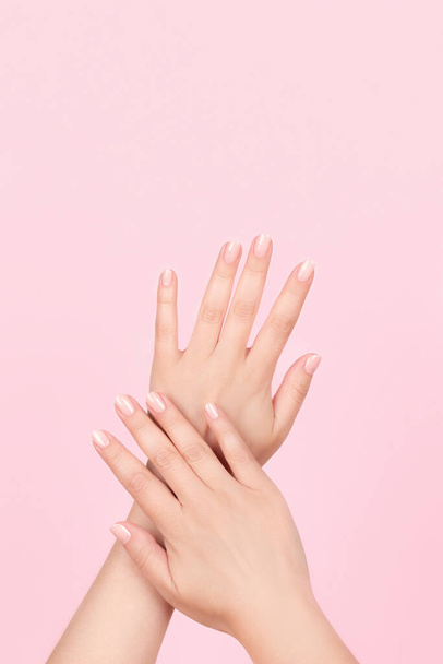 Női kéz gyönyörű manikűr - rózsaszín meztelen körmök rózsaszín háttér. A körömápolás fogalma - Fotó, kép