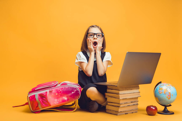 Full length shocked schoolgirl sit behind a stack of books with pc Look at the camera Kids education - Fotoğraf, Görsel