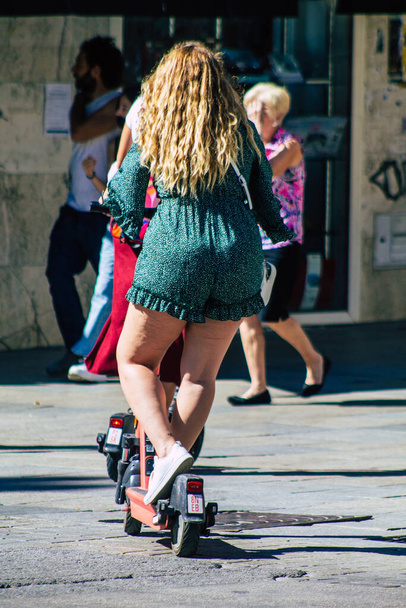 Seville Spain September 18, 2021 People rolling with an electric scooter in the streets of Seville, operating with a small utility internal combustion engines and a deck in the center - Foto, imagen