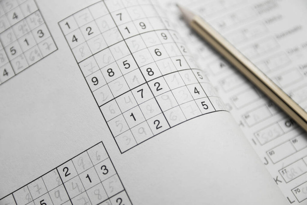 Fertige Sudoku-Rätsel im Vordergrund in einem Hobbymagazin neben einem gelb-schwarzen Bleistift - Foto, Bild