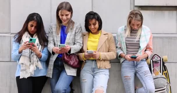 Multiethnische Gruppe schöner junger Freundinnen, die mit mobilen Smartphones an einer Wand stehen - Filmmaterial, Video