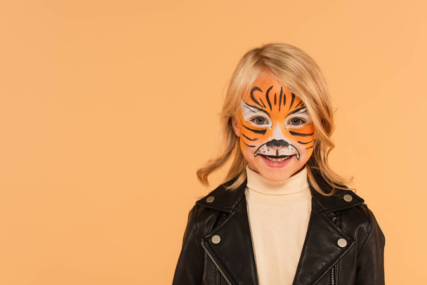 happy child in tiger makeup smiling at camera isolated on beige - Photo, Image