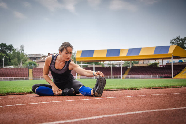 Νεαρή αθλητική γυναίκα τεντώνεται και ετοιμάζεται να τρέξει. ισχυρή αθλητική γυναίκα - Φωτογραφία, εικόνα